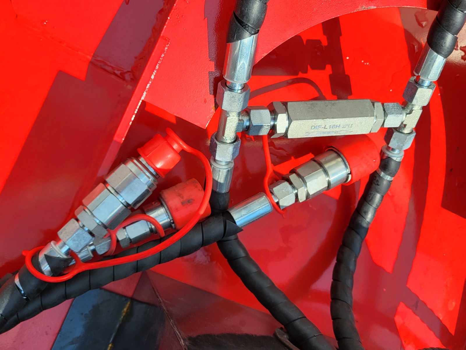 Disc mulcher hydraulic hookup: chrome quick-connect couplers with red caps and a flow valve on red housing
