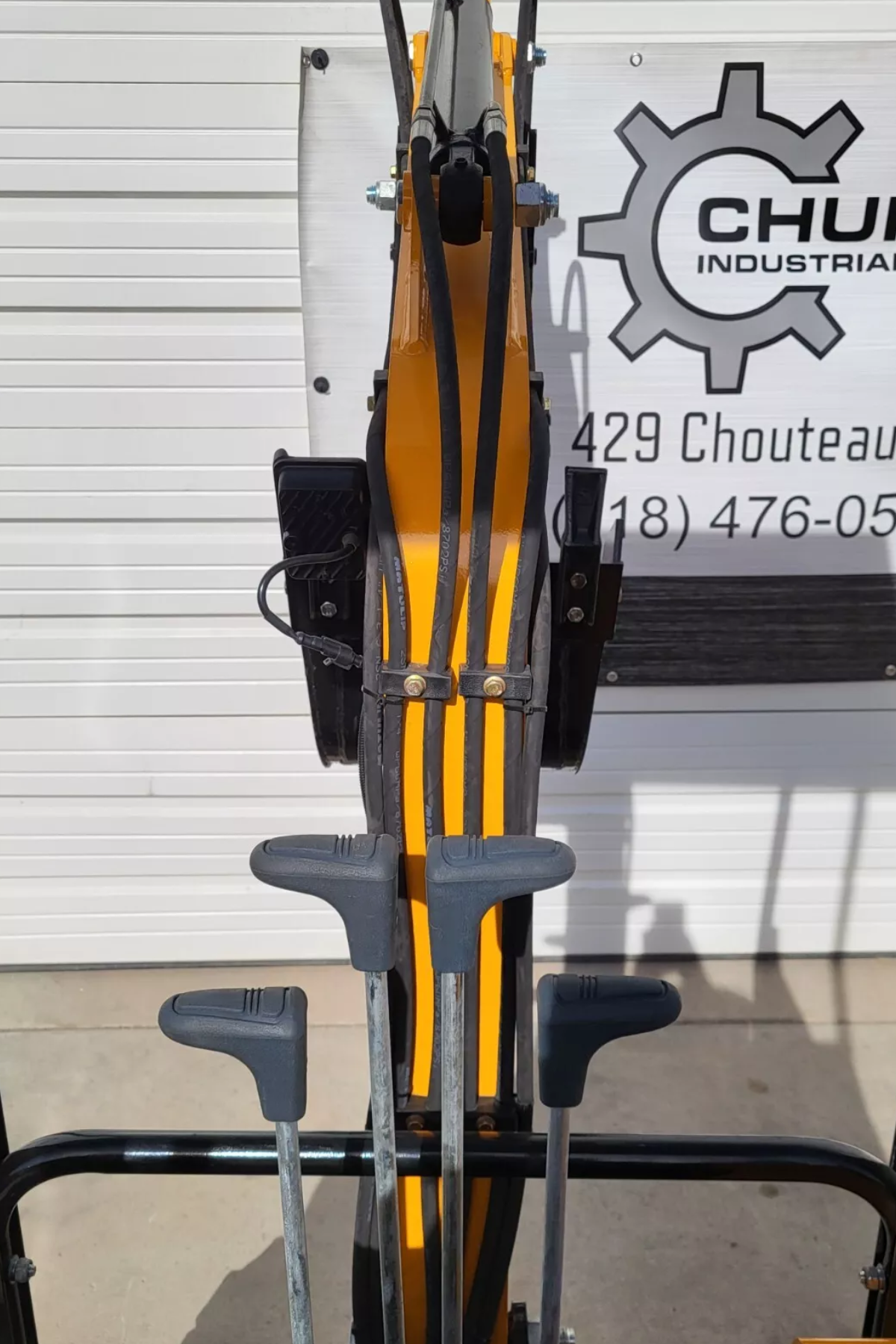 MIVA VA15 operator's view: four T-handle travel and blade levers with the yellow boom and hoses ahead