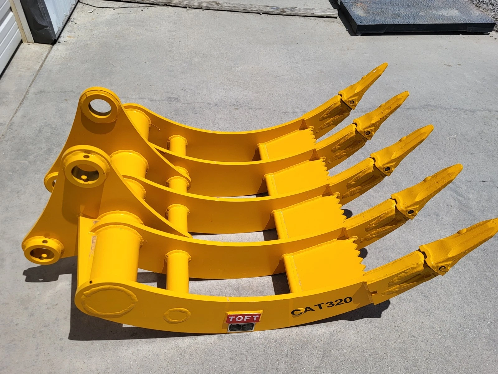 Yellow TOFT08R rake at an angle: pin-boss mounting frame, five curved tines and CAT320 on the edge