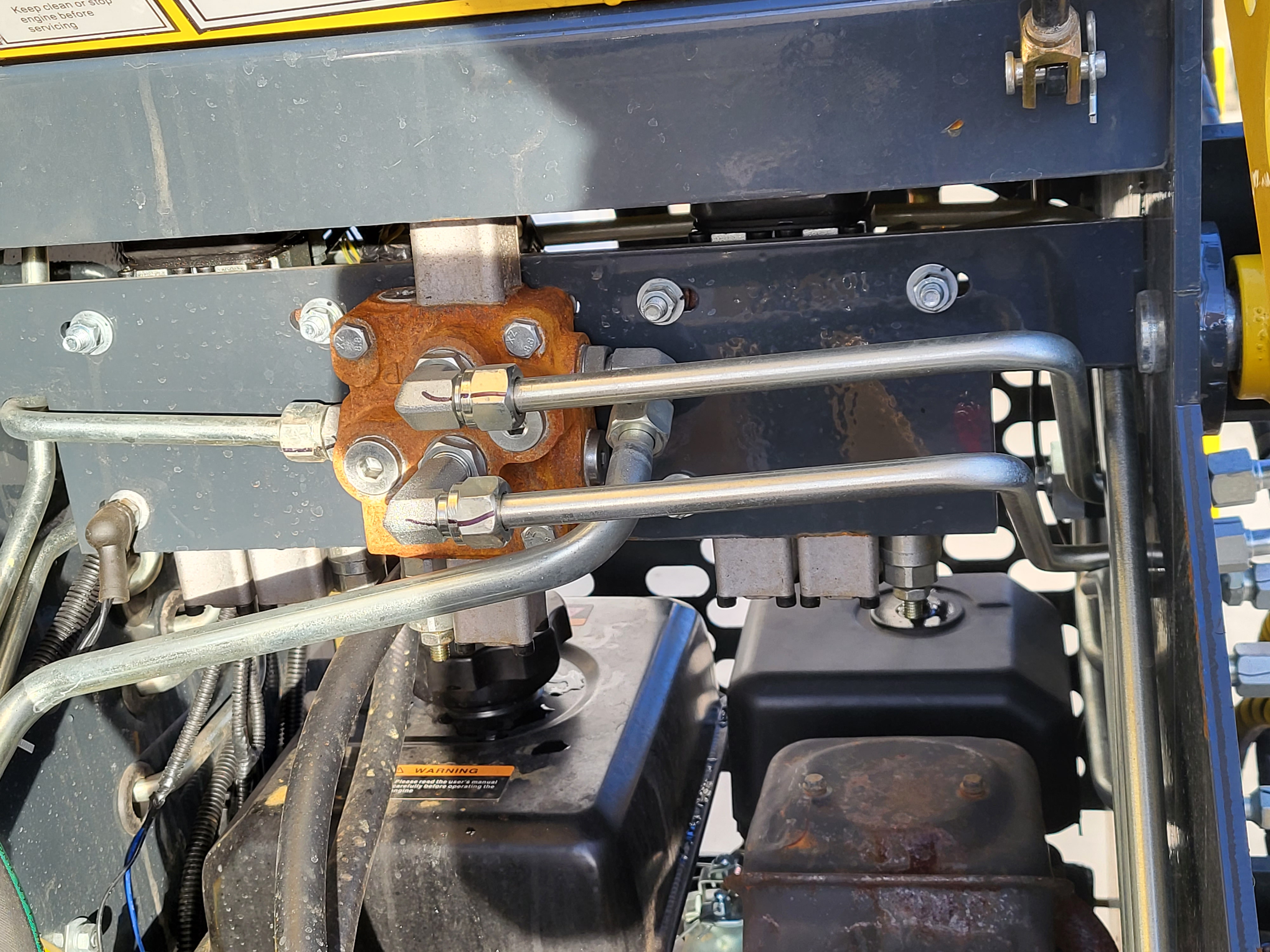 EG360 hydraulic valve block with steel lines, mounted above the engine inside the frame