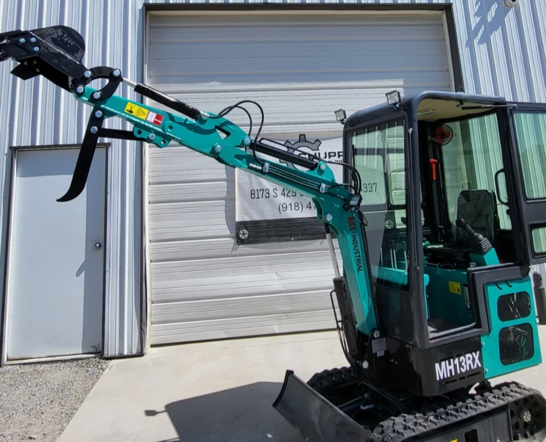 Teal MH13RX mini excavator with boom extended, toothed bucket and thumb raised, enclosed cab and rubber tracks