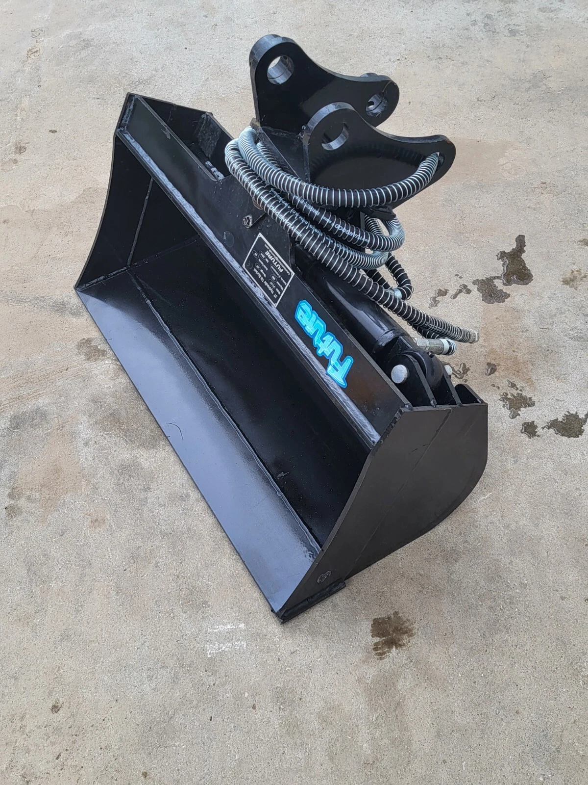 Black Future hydraulic tilt bucket, open shell interior with tilt head, data plate and coiled hoses