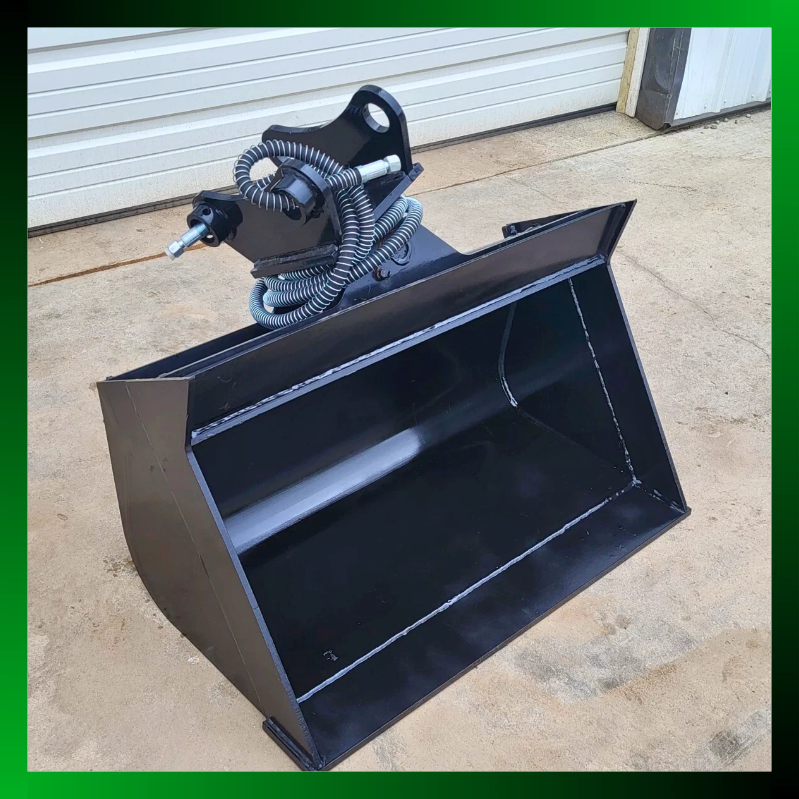 Black hydraulic tilt bucket at an angle, wide open shell with tilt coupler and coiled hoses above
