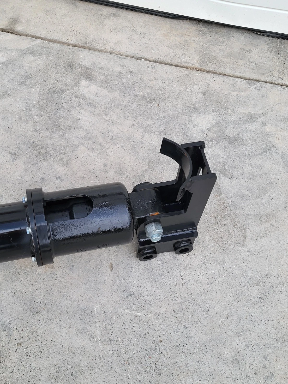 Auger drive housing bolted to its quick-attach mounting bracket with twin pin lugs