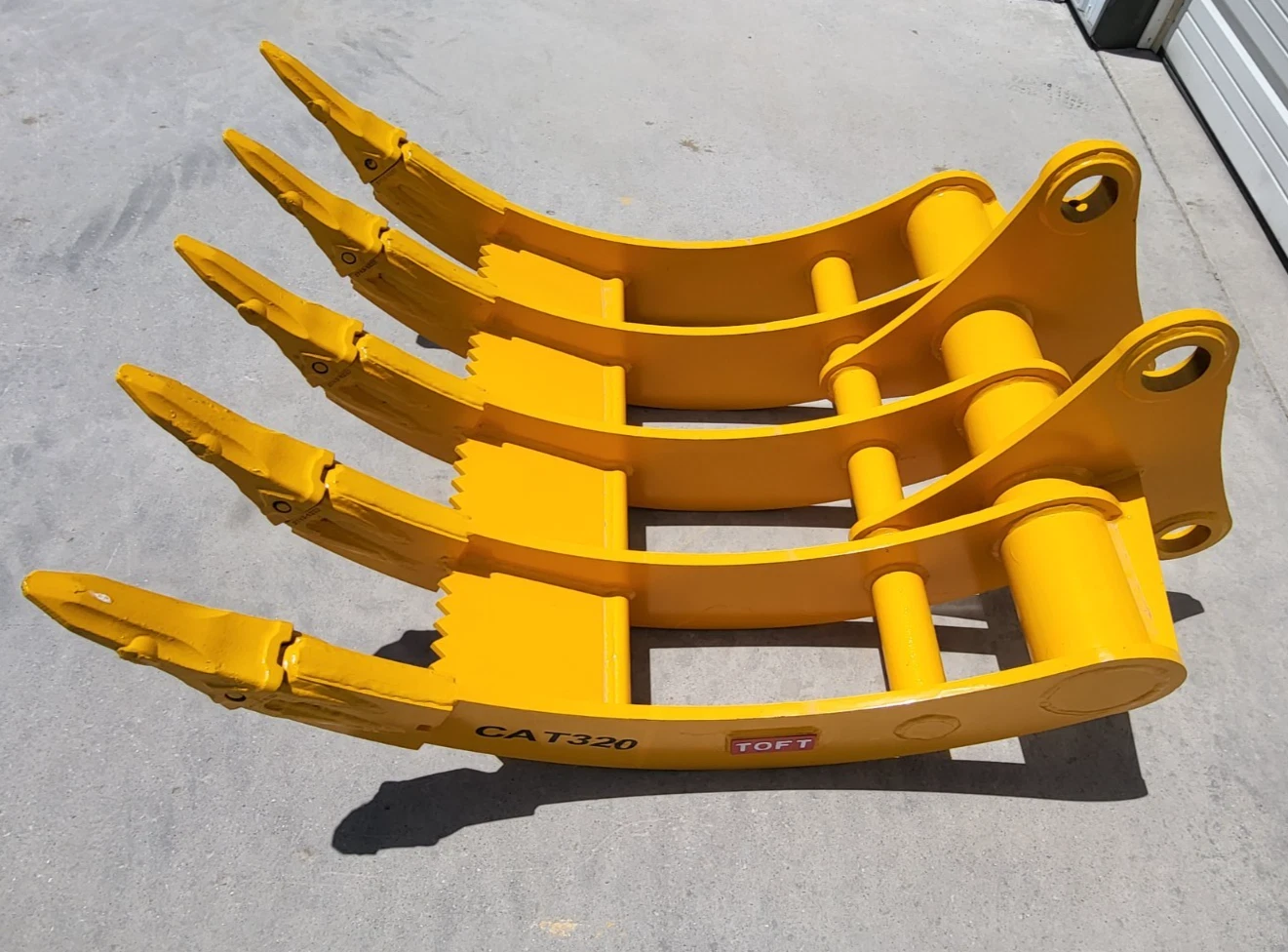 Yellow TOFT08R excavator rake from above, five curved tines with bolted tips, CAT320 marked on the frame