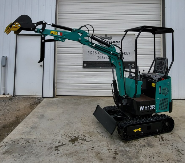 Teal WH12R mini excavator with boom fully extended, digging bucket and fixed thumb, blade lowered