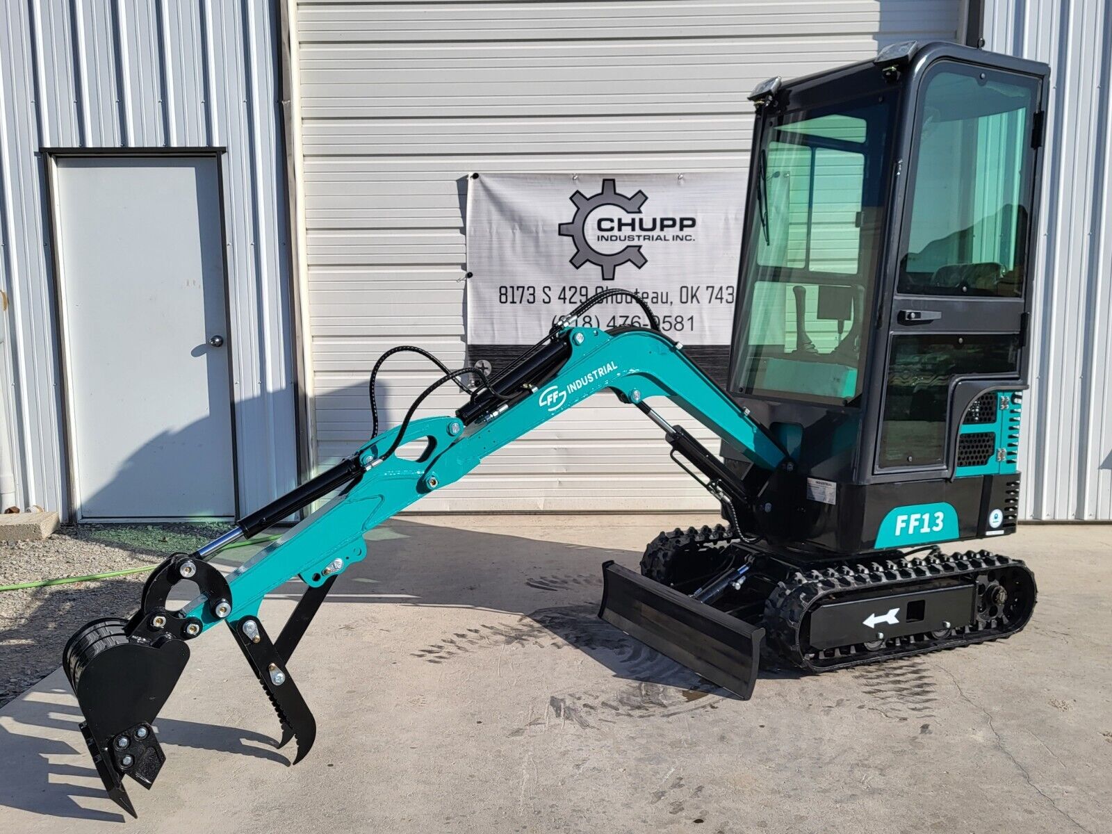 FF13 mini excavator with the boom extended, hydraulic thumb over the digging bucket and the dozer blade lowered