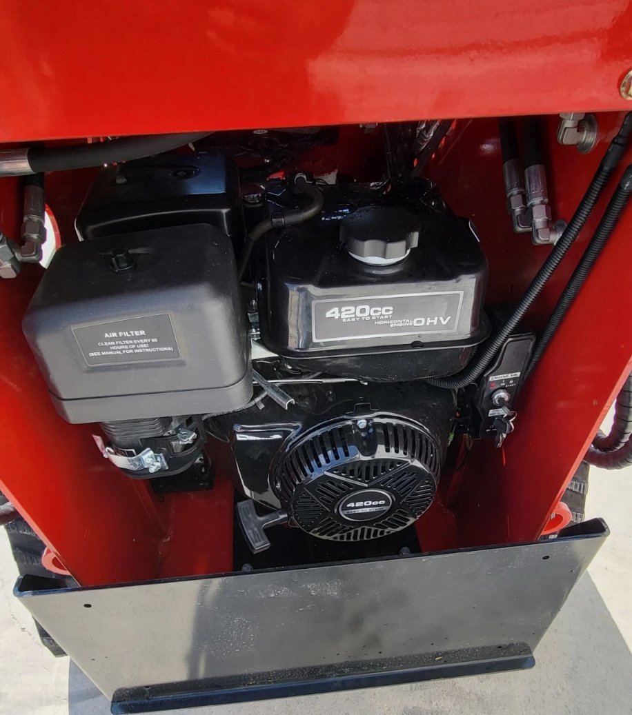 420cc OHV horizontal engine with air filter and recoil start under the red mini skid steer's rear hood