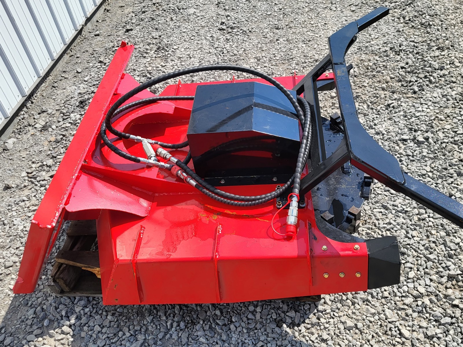 Red disc mulcher from above: black hydraulic motor, coiled hoses with quick couplers and quick-attach mount