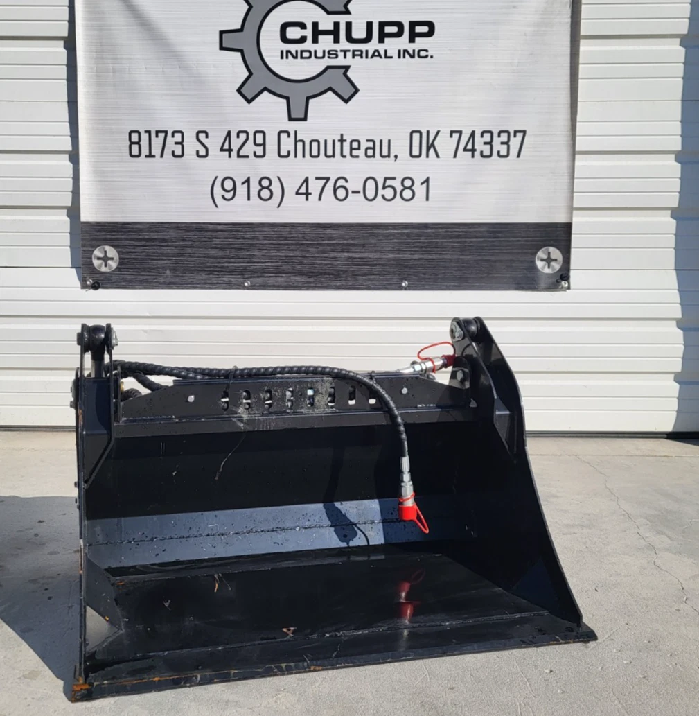 Black 4-in-1 skid steer bucket below the Chupp Industrial banner, hydraulic hose and red-capped coupler