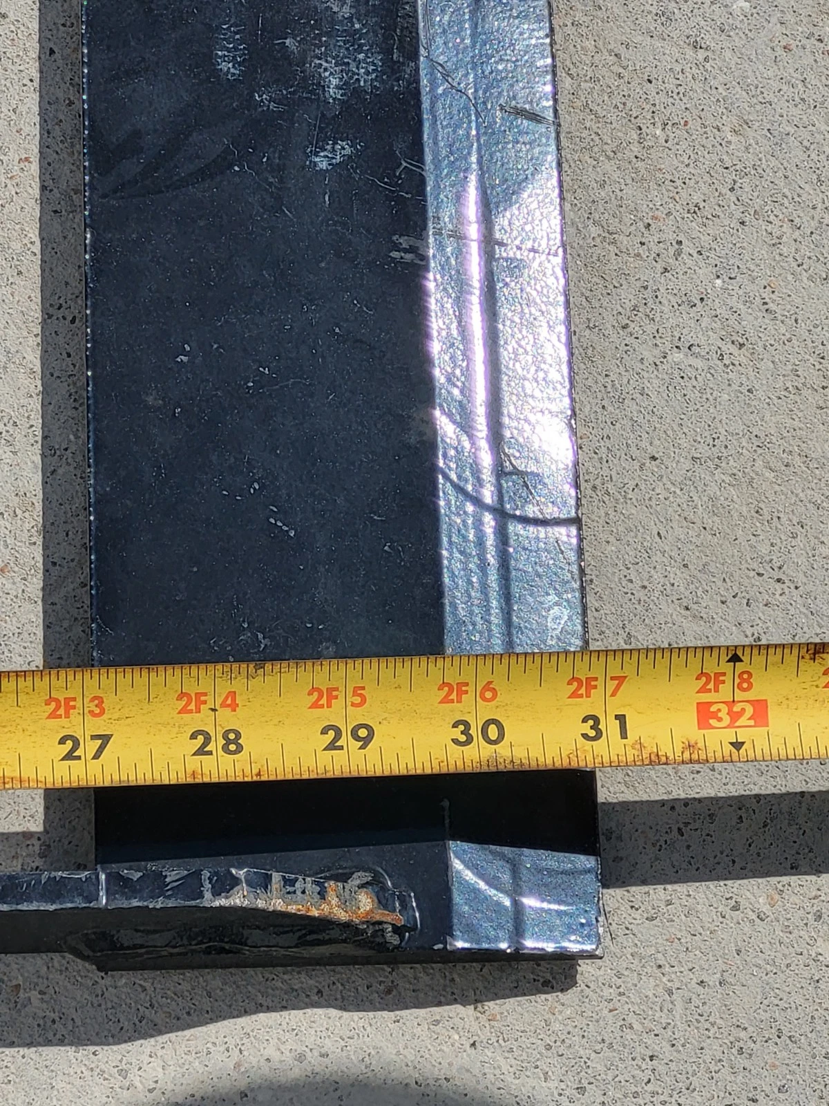 Tape measure across the land leveler's flat steel blade, extended past 31 inches