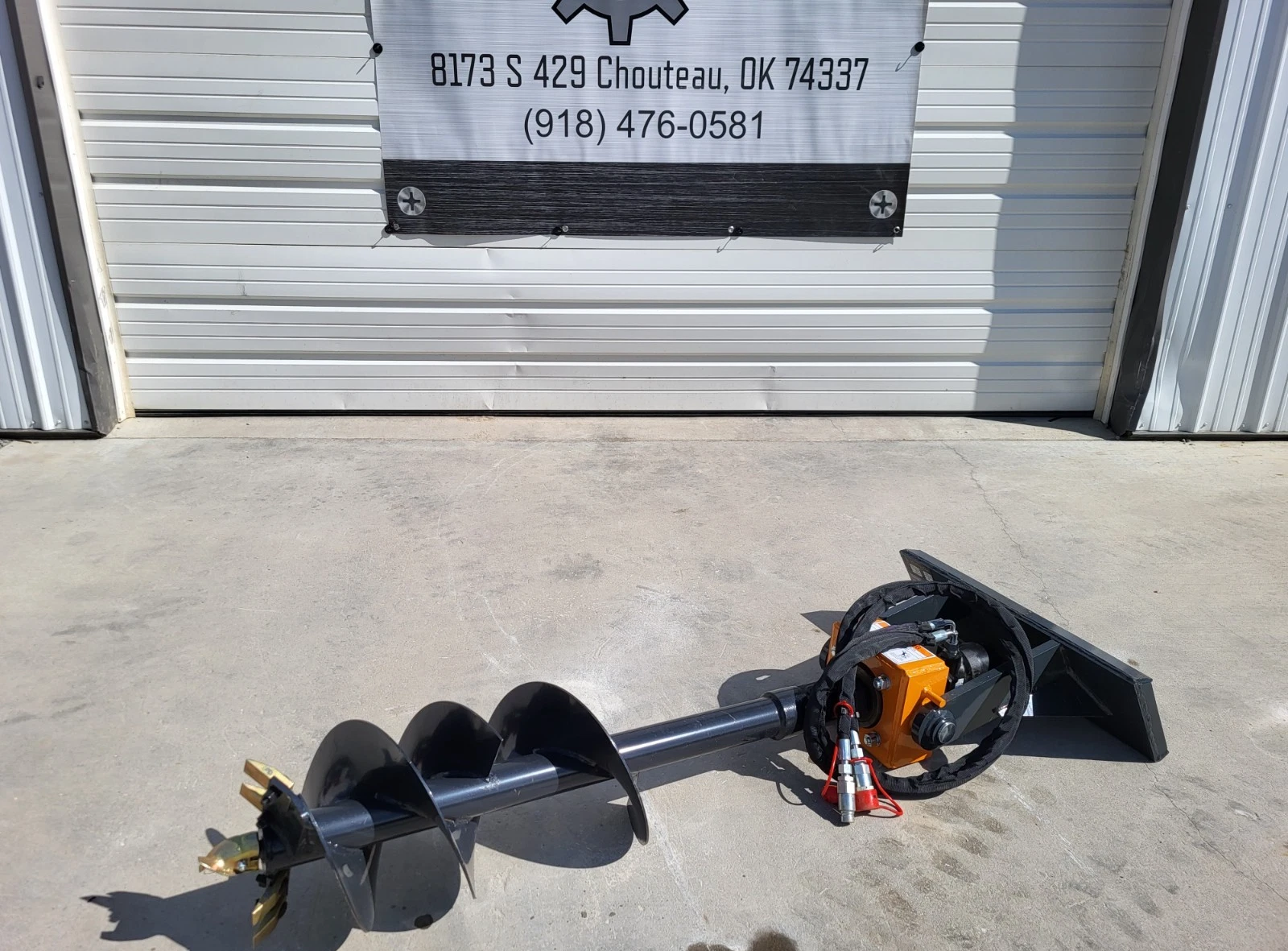 Mini skid steer auger laid out full length: black flighted bit, orange drive gearbox and quick-attach mount plate