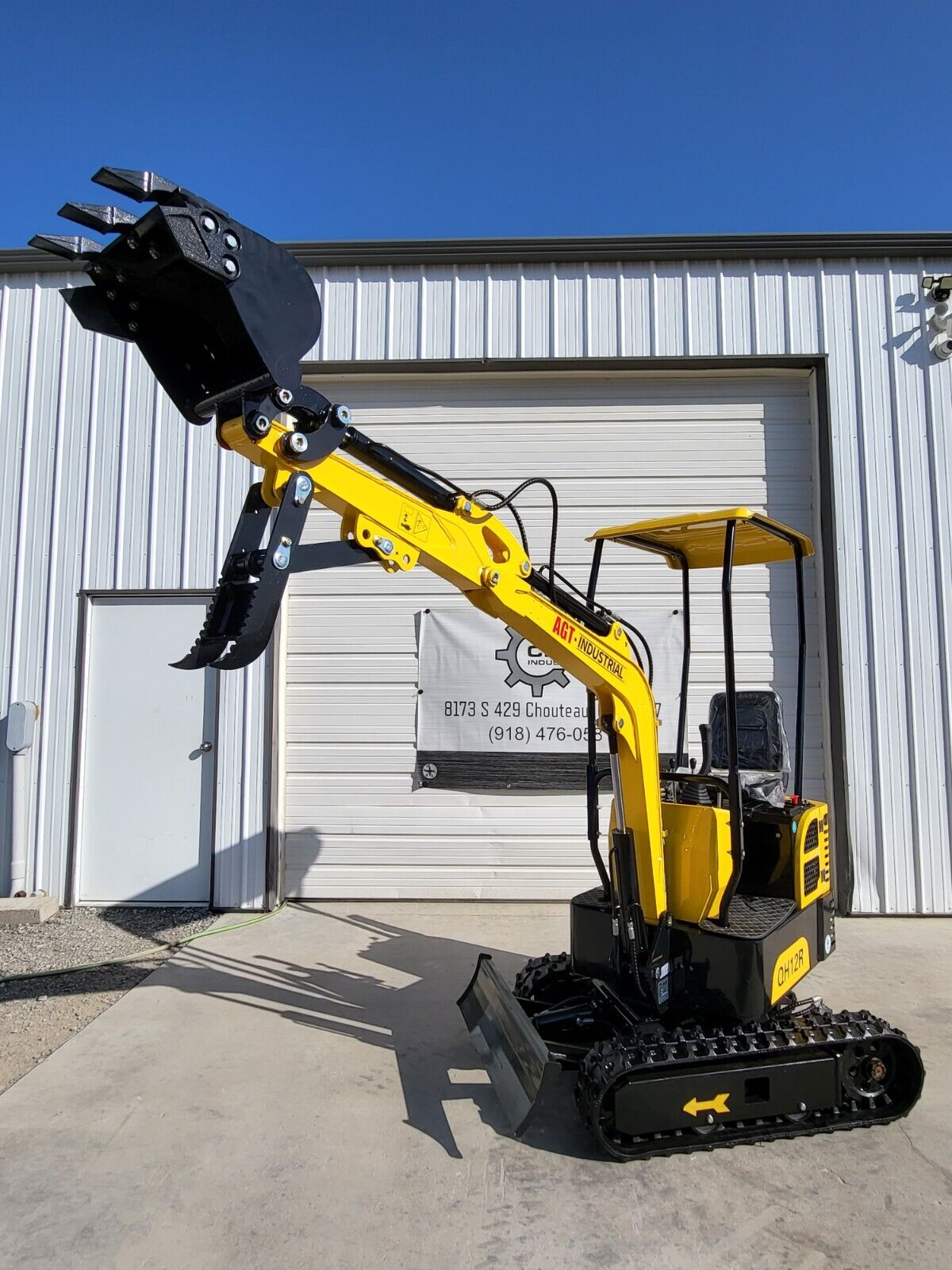 AGT QH12R mini excavator with boom raised, toothed bucket and fixed thumb above the backfill blade