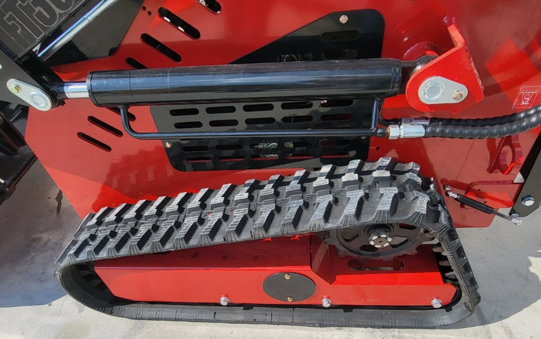 Rubber track undercarriage of the red mini skid steer, drive sprocket and lift cylinder above