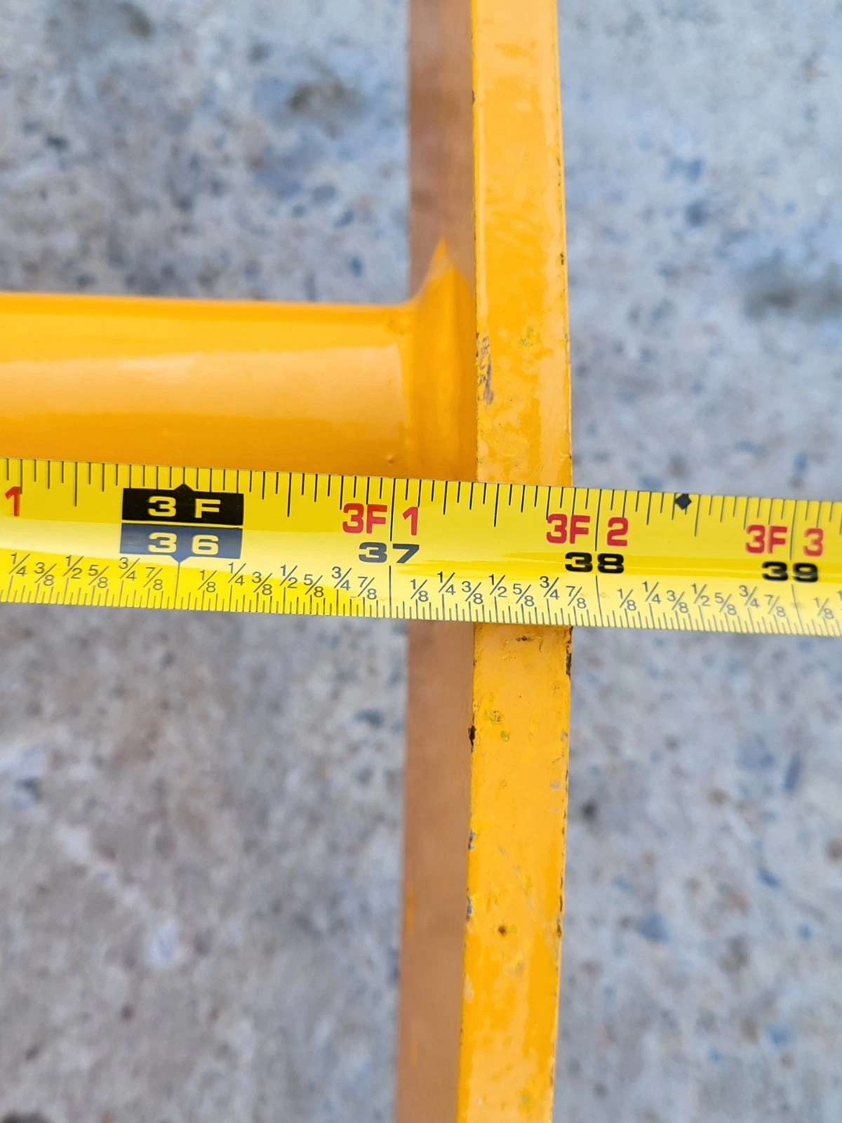 Tape measure across the yellow rake's frame, scale reading just past 38 inches