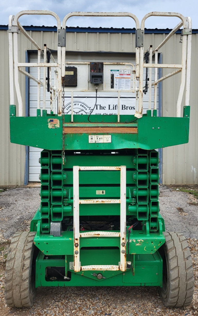 Green JLG 4069LE rough terrain scissor lift, end view, folded white guardrails and scissor stack, large tires