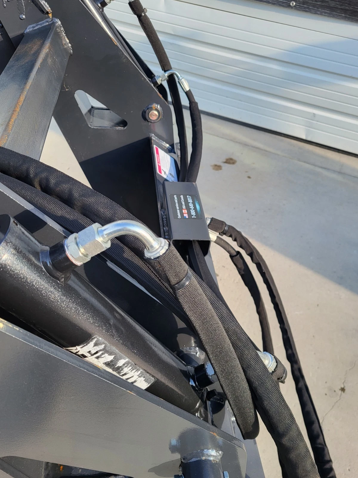 Log grapple hose guard block with sleeved hydraulic lines and cable routing