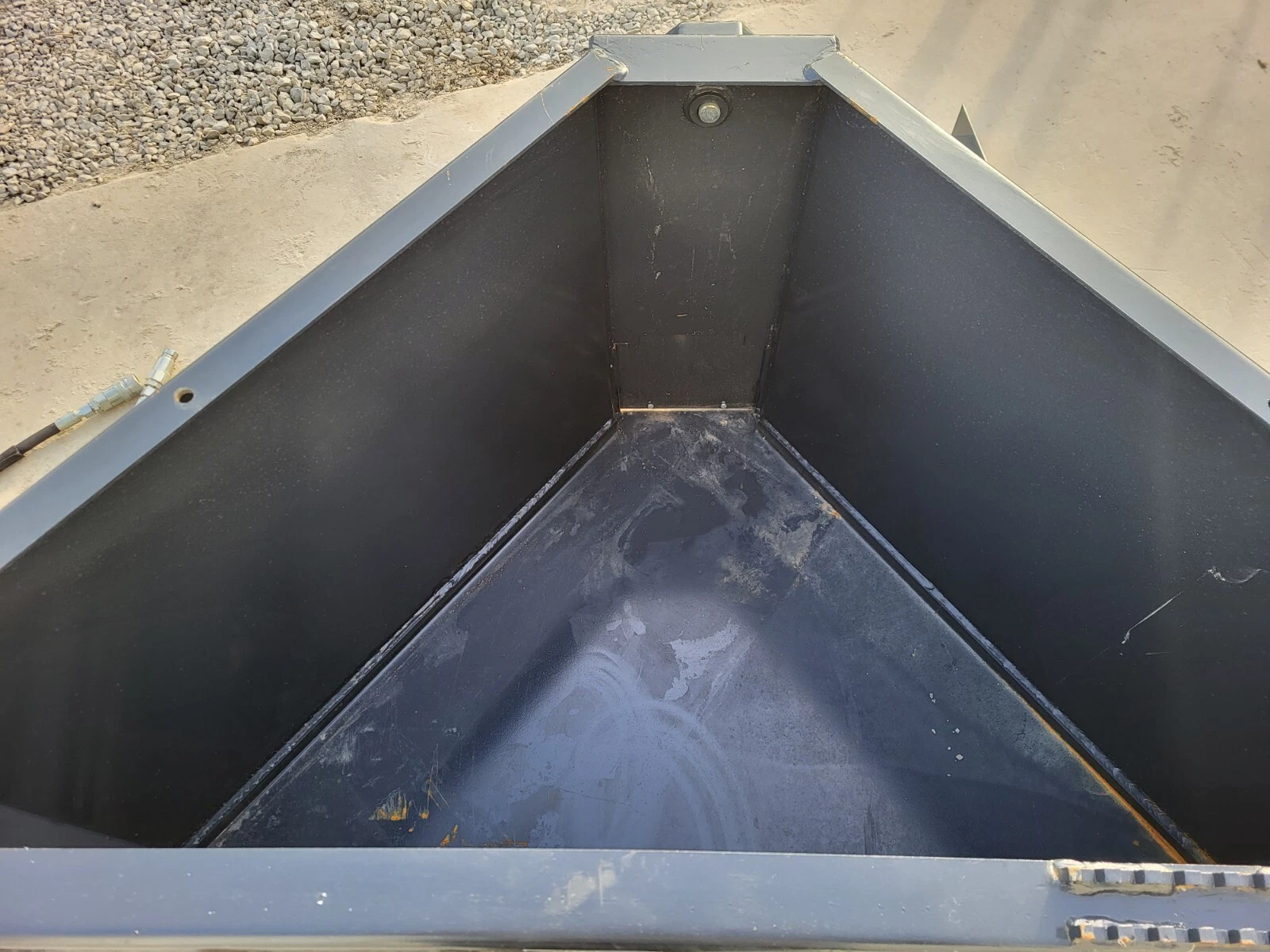 Inside the concrete bucket: sloped steel walls funneling down toward the discharge opening