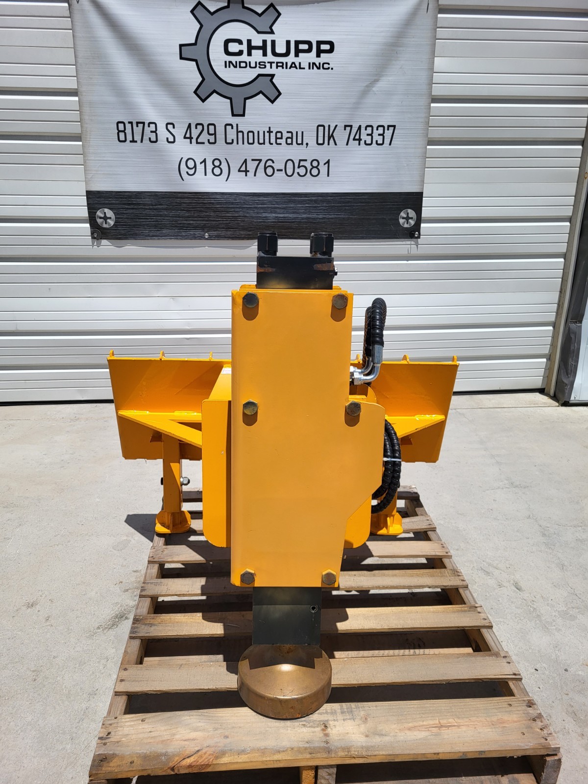 Yellow hydraulic post driver on a pallet: quick-attach mount wings, supply hose and domed driver head