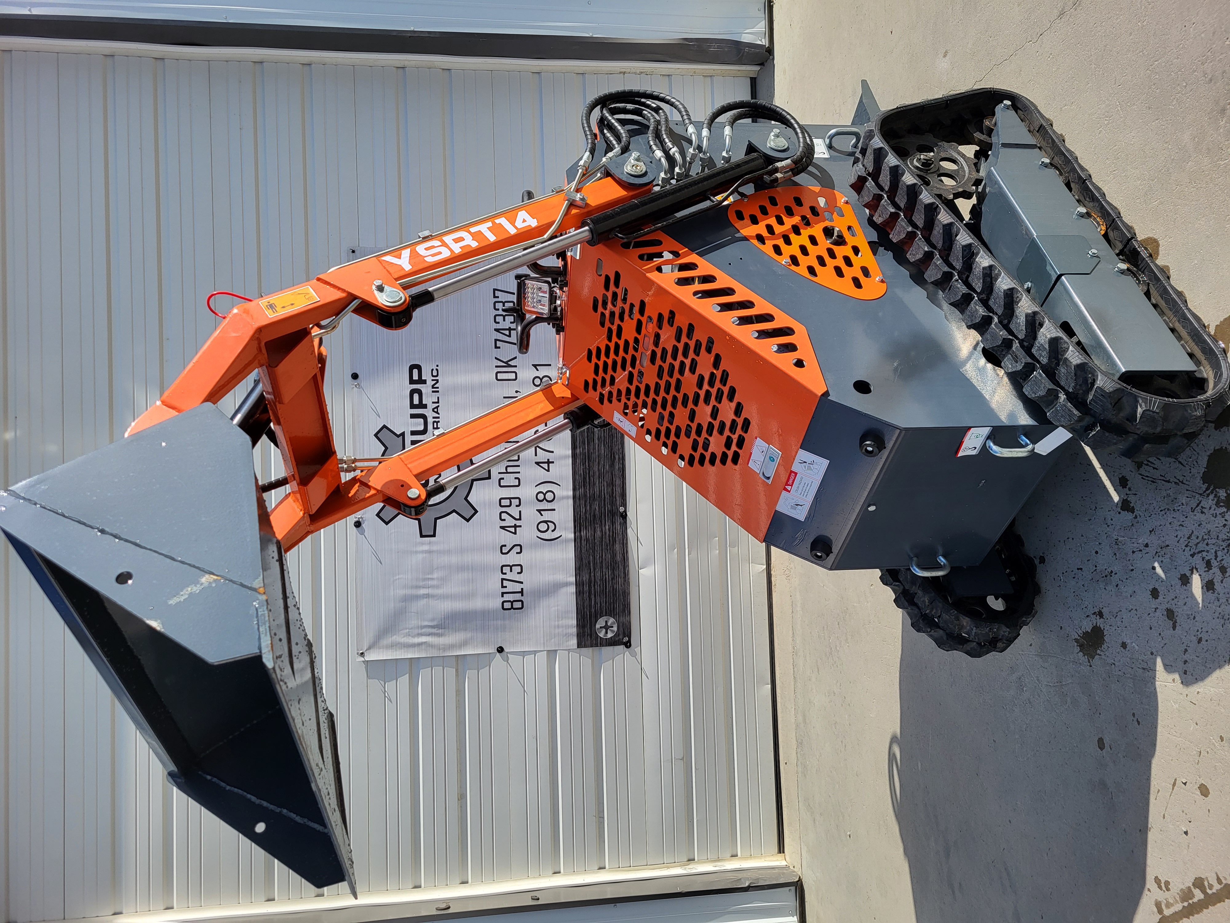 AGT YSRT14 stand-on mini skid steer, orange loader arms with a gray bucket, vented engine cowl and rubber tracks