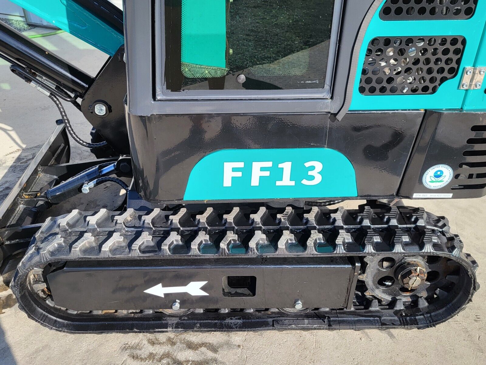 FF13 rubber track and steel drive sprocket below the black upper housing, with the model decal and EPA label