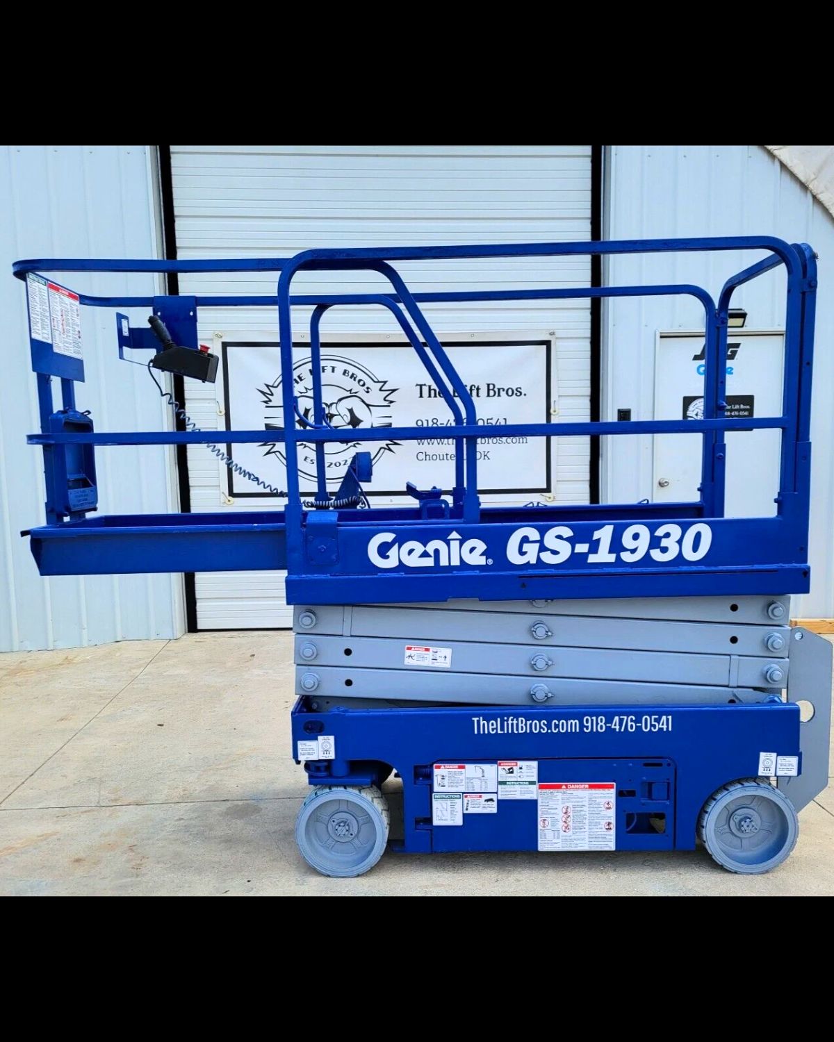 Genie GS-1930 scissor lift in blue with the slide-out extension deck pushed out, guardrails up, platform lowered