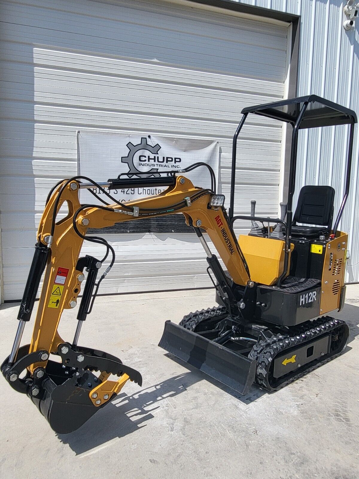 AGT H12R mini excavator with the boom folded in, hydraulic thumb clamped over the toothed bucket, LED work light