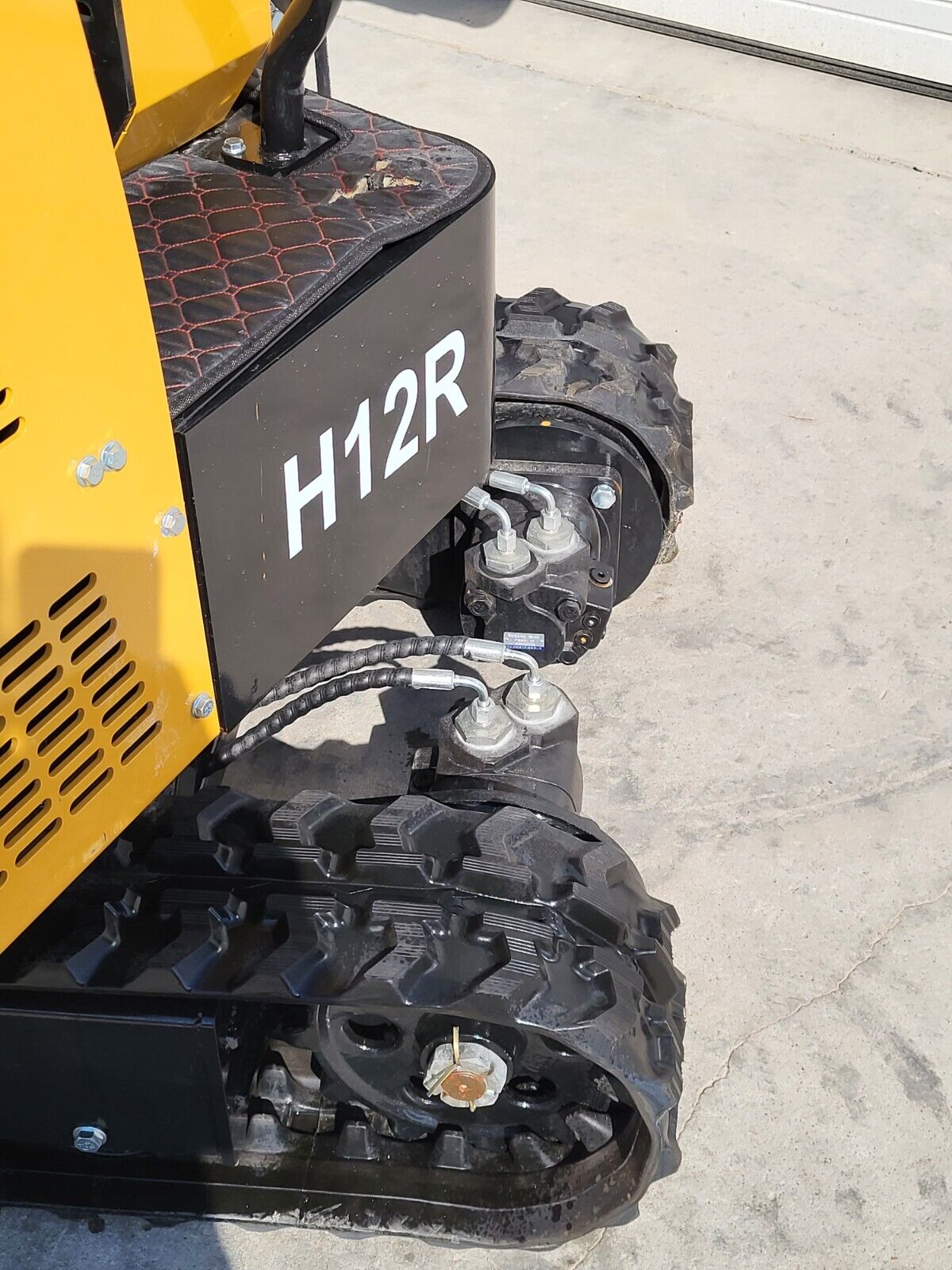 H12R decal on the AGT mini excavator counterweight, with track drive motor, hydraulic hoses and rubber tracks