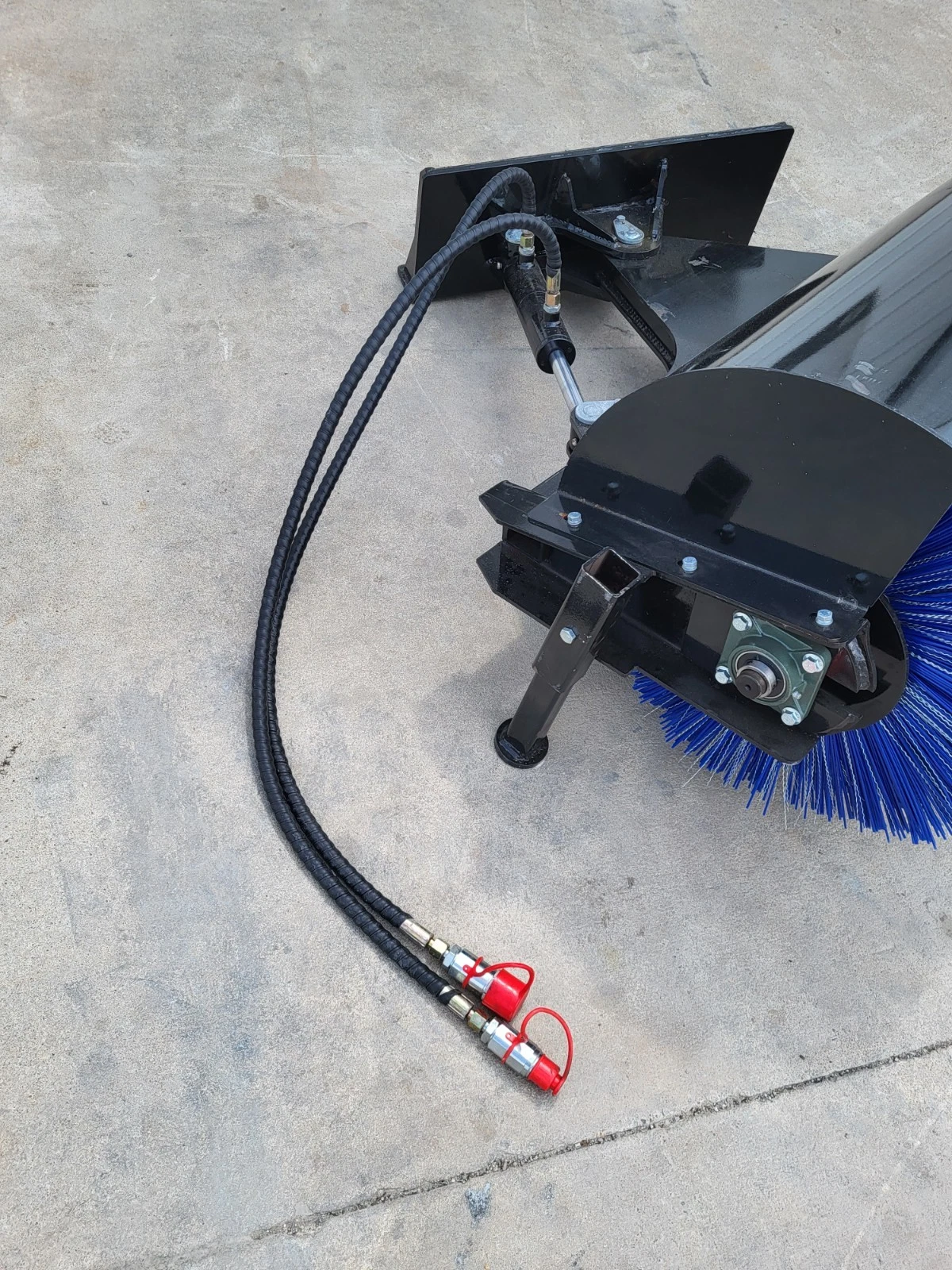 Angle broom's mount plate and angle cylinder with hoses running to red-capped quick couplers