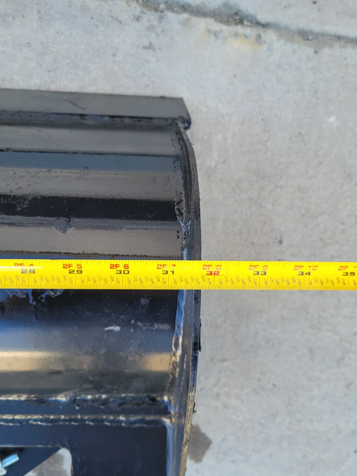 Tape measure across the tilt bucket's top edge, reading 32 inches