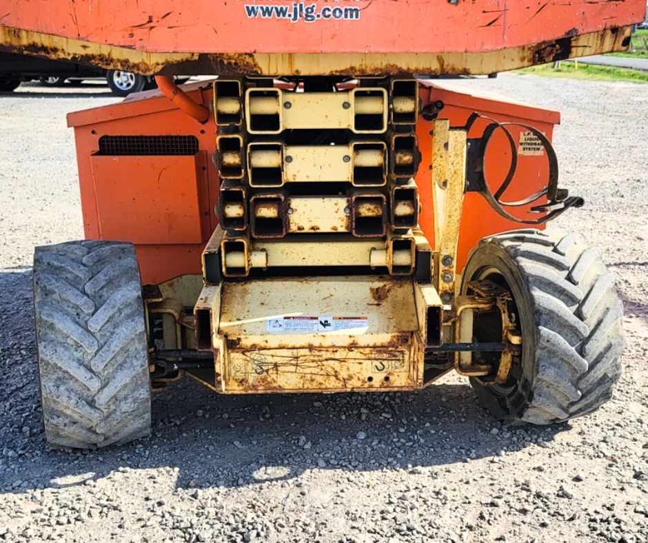 JLG rough terrain scissor lift from the rear: stacked scissor arms, engine cover and four-wheel-drive lug tires