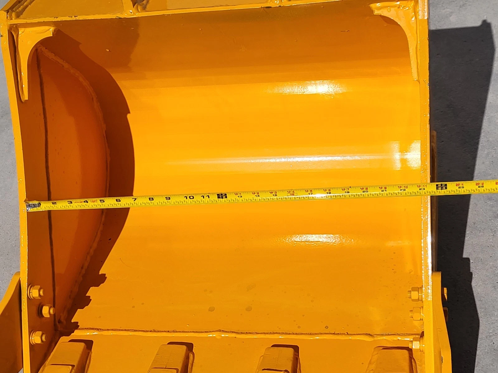 Tape measure across the inside of the yellow bucket, reading past 24 inches from wall to wall