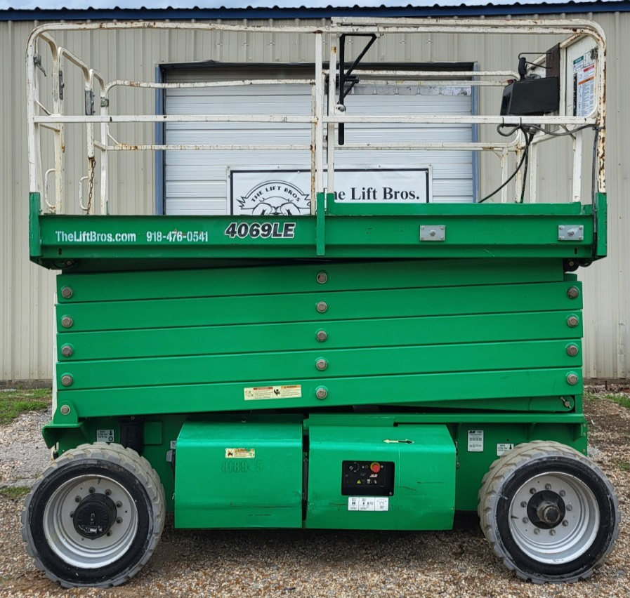 Green JLG 4069LE rough terrain scissor lift, side view, platform lowered, large treaded drive tires