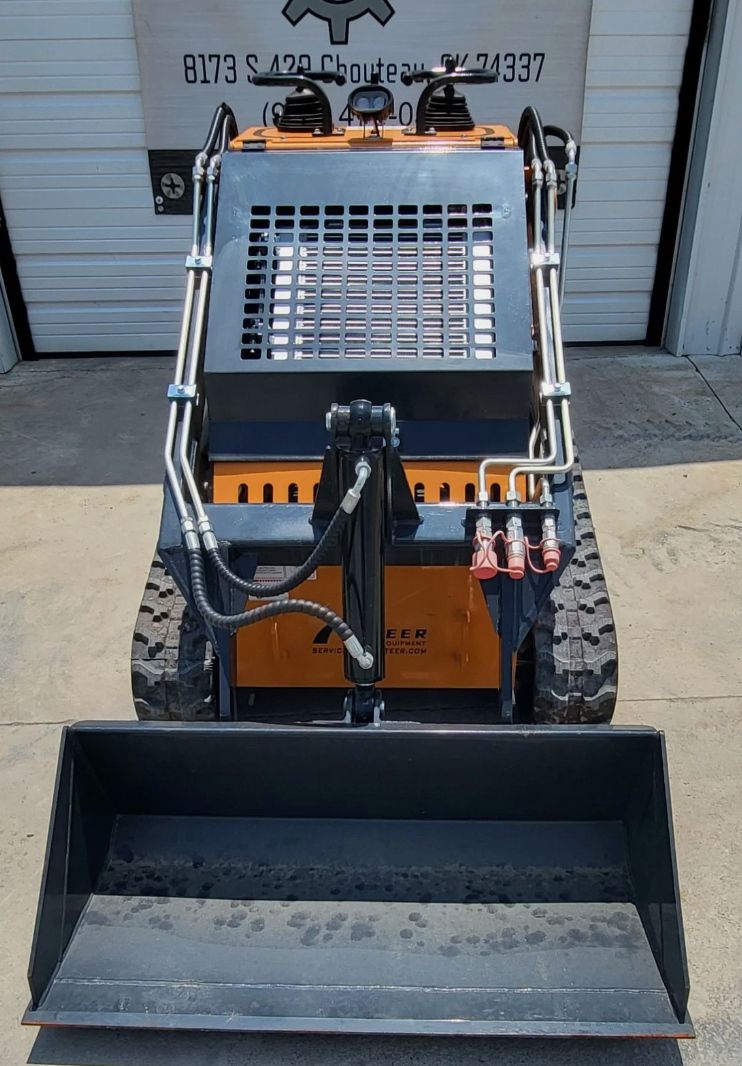 QB-480 mini skid steer head-on: dirt bucket on the quick-attach, red hydraulic couplers and rubber tracks
