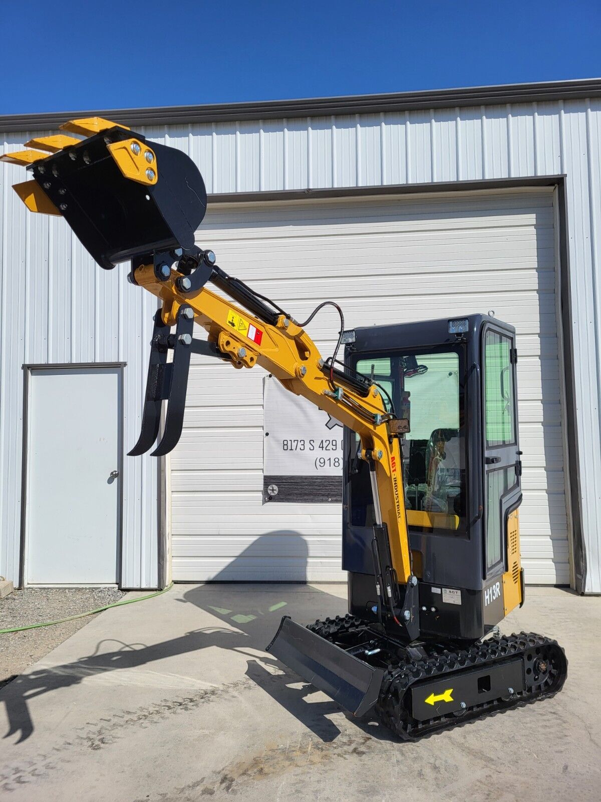 AGT H13R mini excavator with boom raised and the toothed bucket curled at full dump height, thumb open