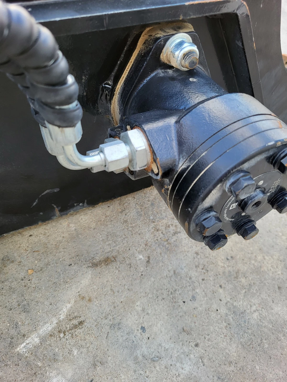 Hydraulic drive motor bolted to the sickle mower frame, steel hard line and hose fitting at the port