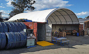 26x40x10 container roof shelter in use: white arch cover spanning two shipping containers over a work area