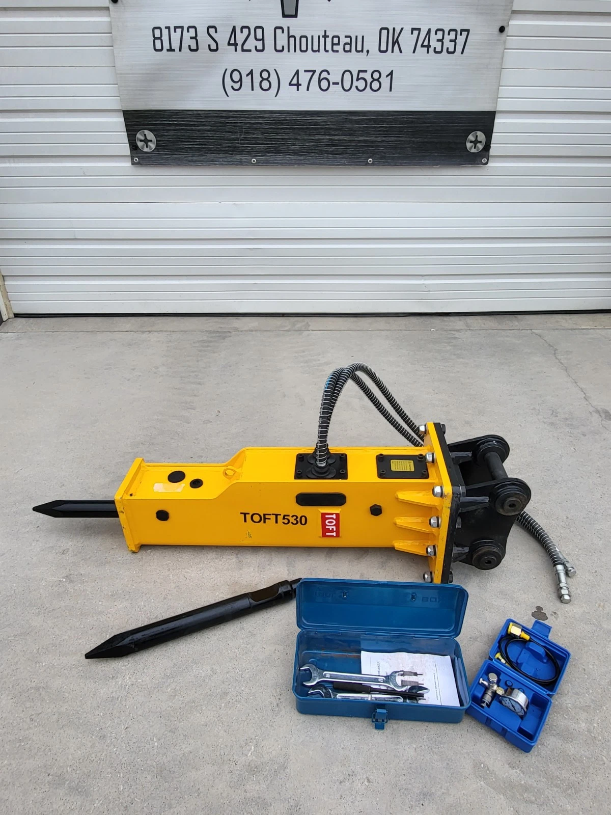 TOFT530 yellow hydraulic breaker standing upright with hoses, spare moil point, wrench box and charge kit