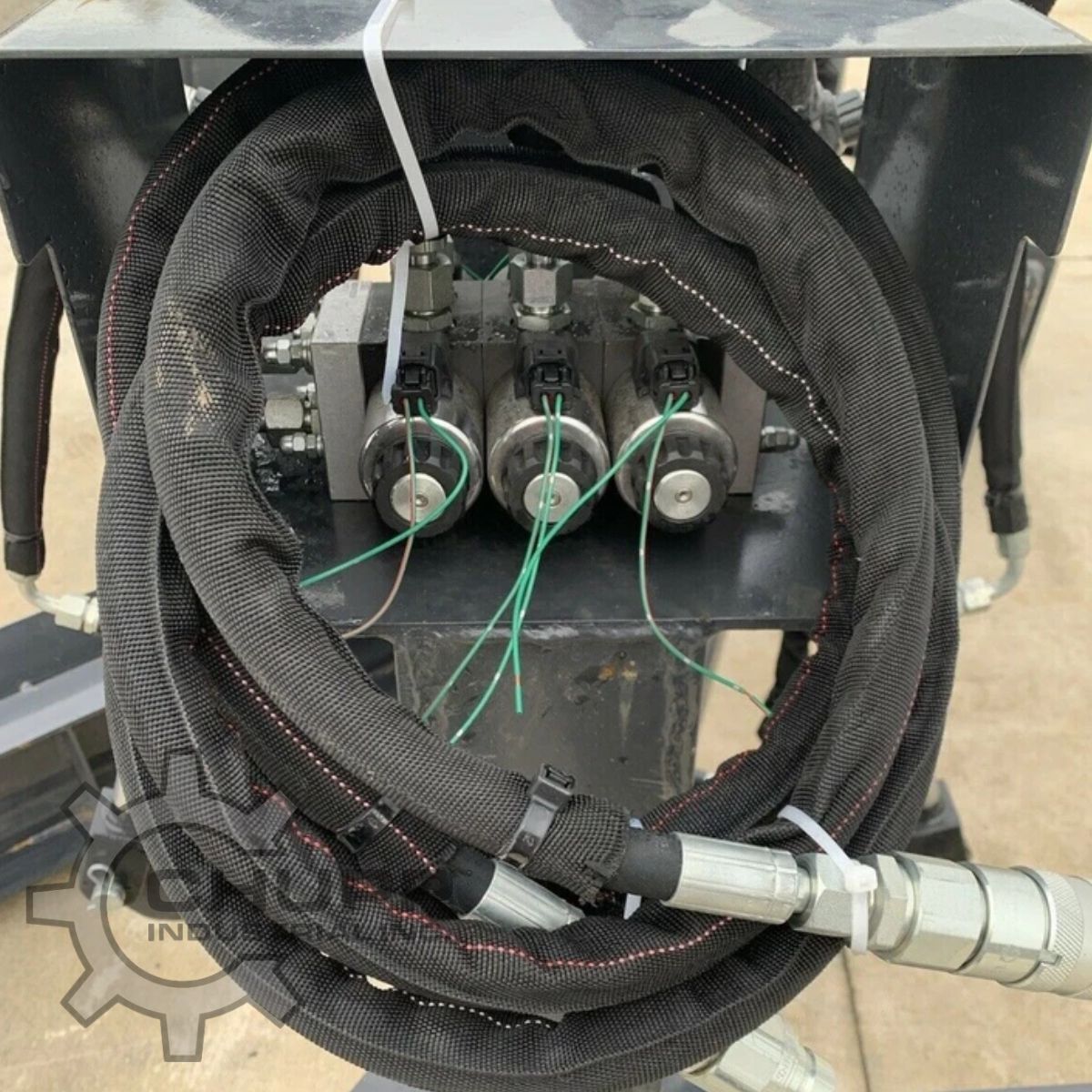 Three-spool electric solenoid valve bank and coiled hydraulic hoses with flat-face couplers on the grading blade