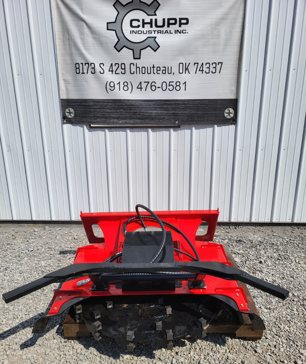 Red disc mulcher on a pallet, hydraulic drive motor and hoses on top, toothed cutting disc below