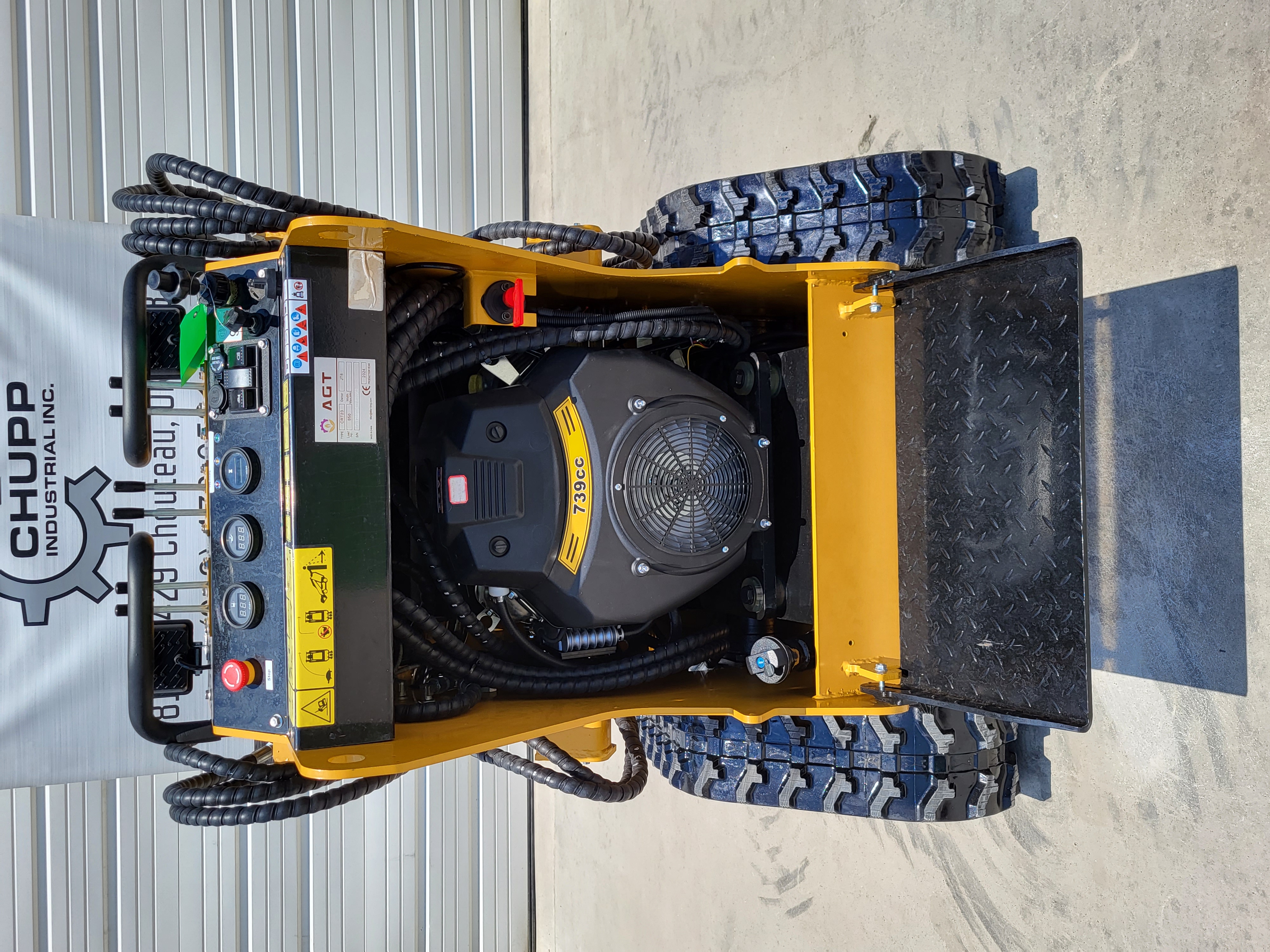 AGT CRT23 mini skid steer from above: 739cc engine, gauge panel with red stop button, rubber tracks and fold-down platform