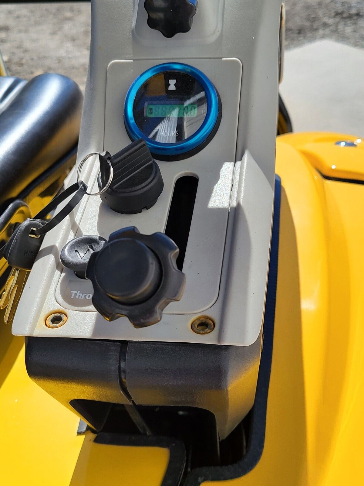 FF15 side console: blue-bezel hour meter, key ignition with the keys in it, and the throttle knob below