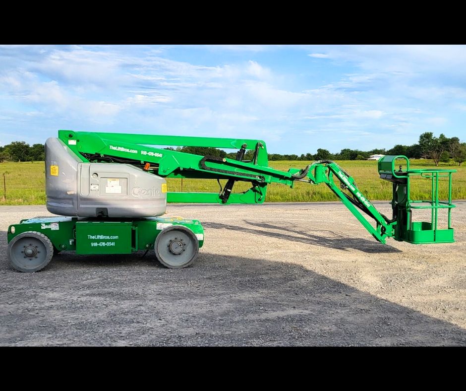 Green Genie articulating boom lift, gray turret, boom lowered and stretched out level with the platform near the ground