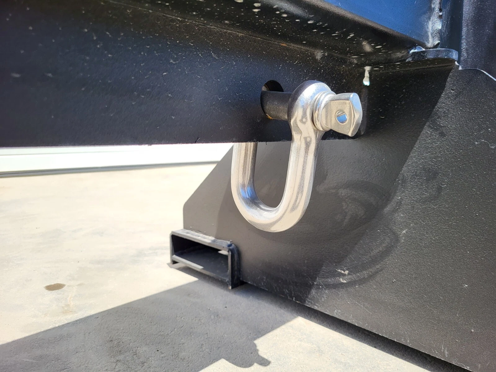 Screw-pin D-shackle pinned through a lug on the forklift jib's mounting frame