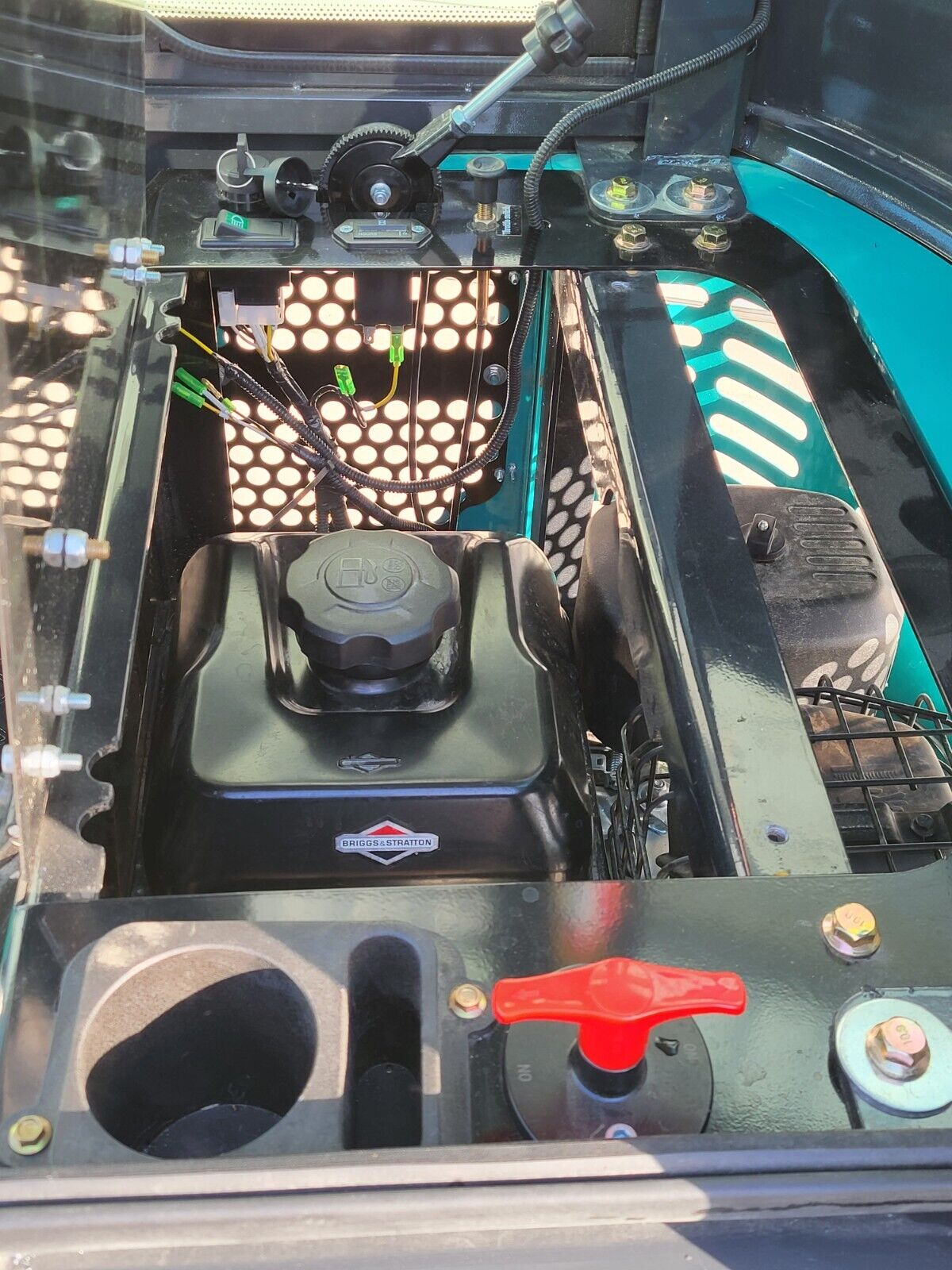 FF13 engine compartment behind the seat: Briggs & Stratton engine, fuel cap, red battery disconnect and hour meter