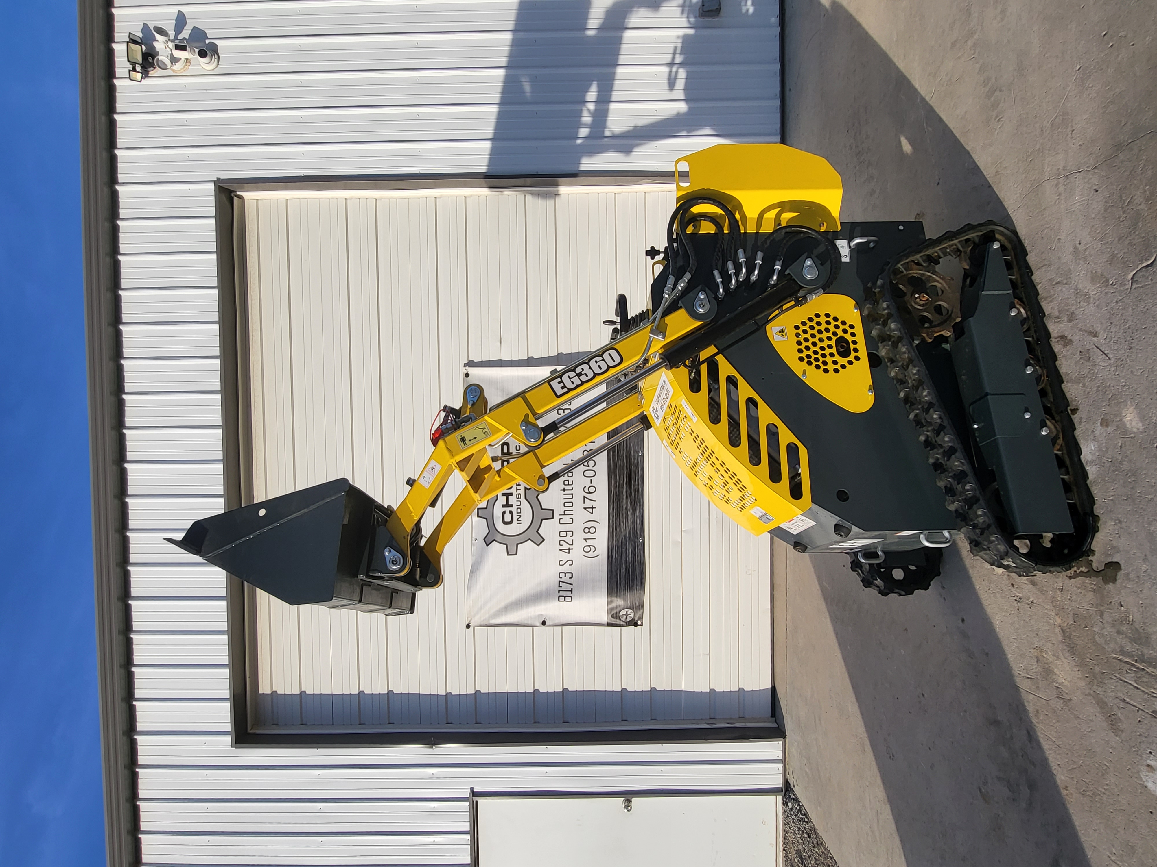 EGN EG360 mini skid steer with the loader arms raised and the bucket lifted high, rubber tracks and drive sprockets