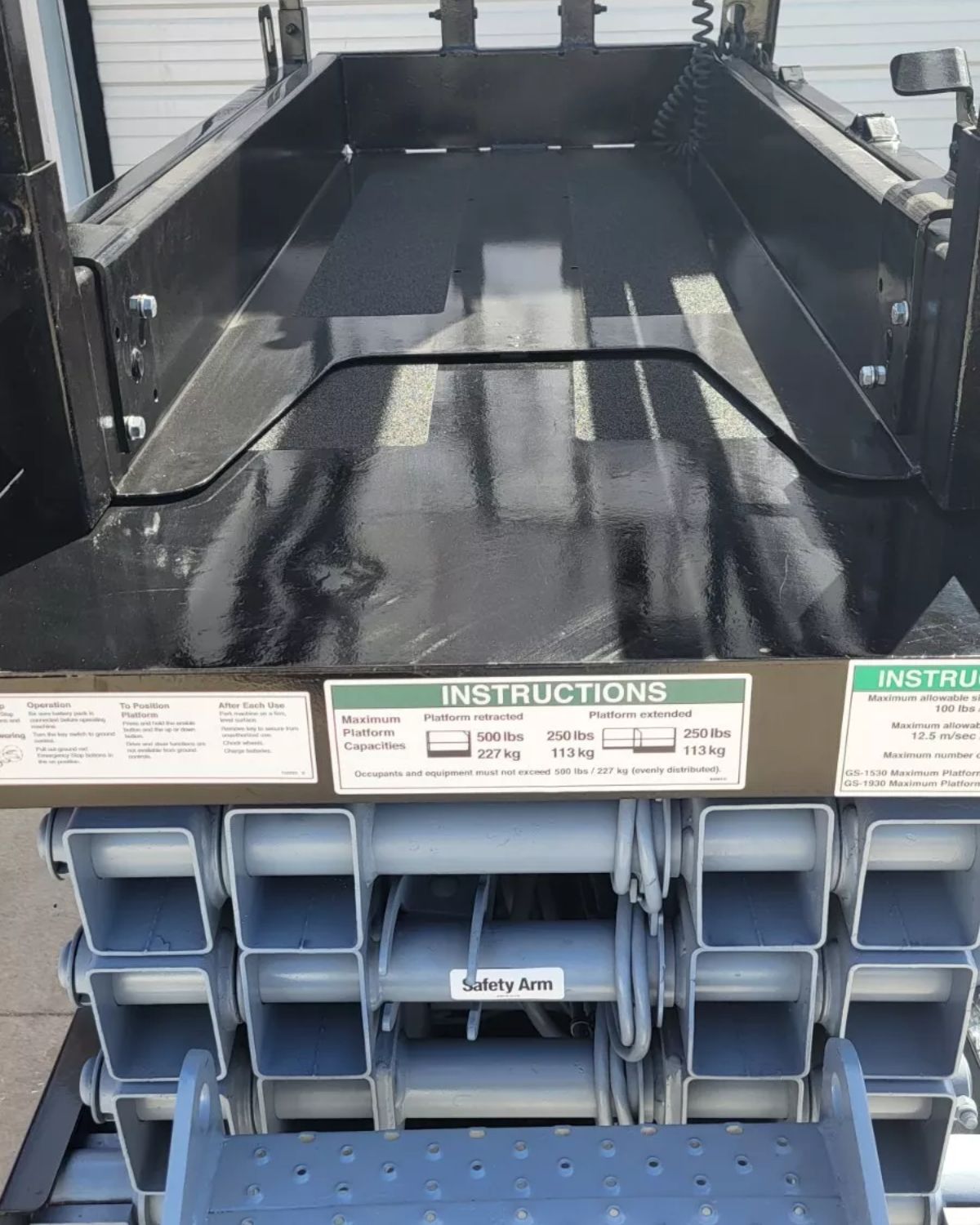 Genie GS-1930 platform deck with its slide-out extension, capacity placards and the scissor stack underneath