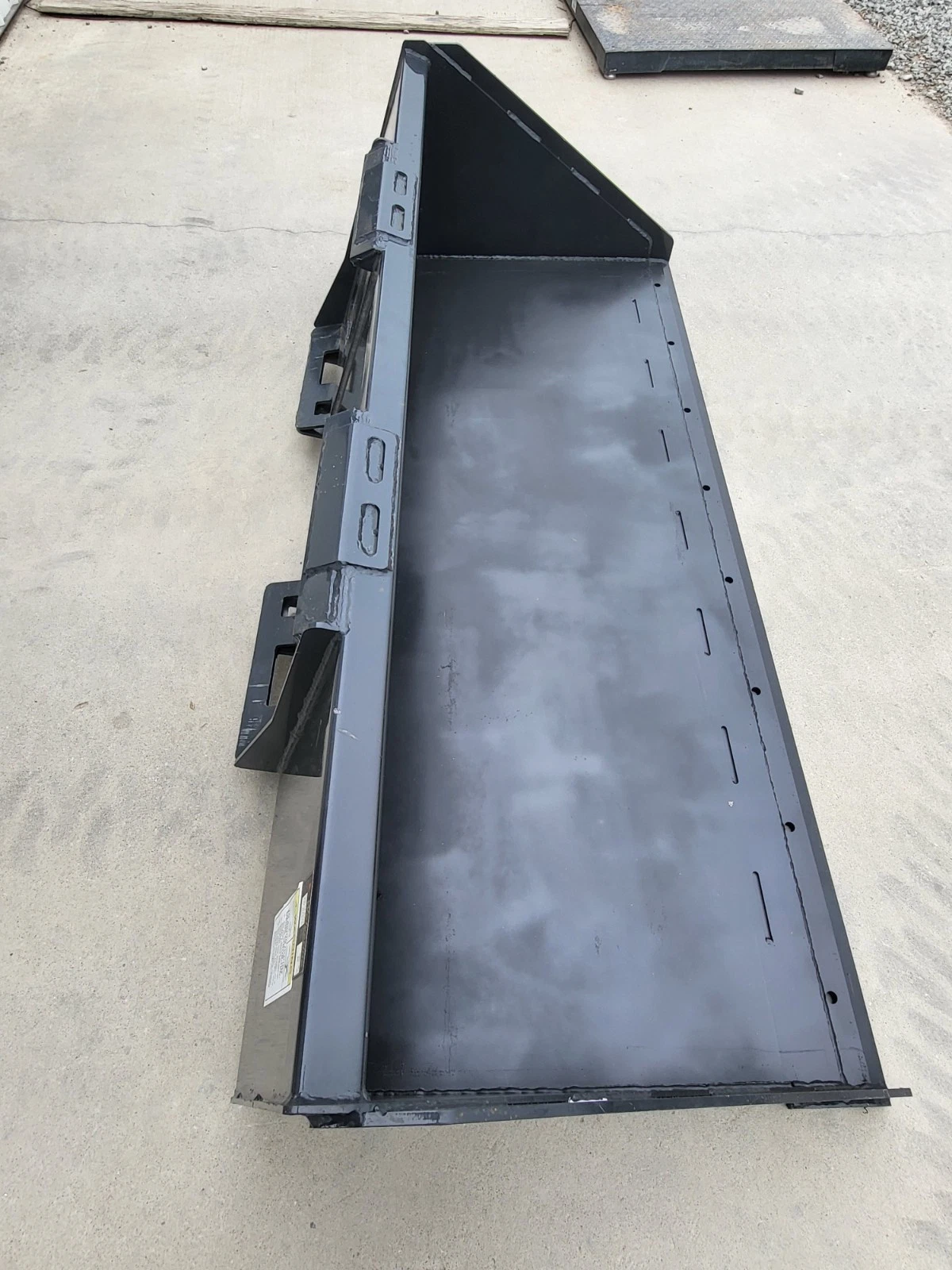 Wolverine 84-inch skid steer bucket from above: interior floor, side walls and quick-attach brackets