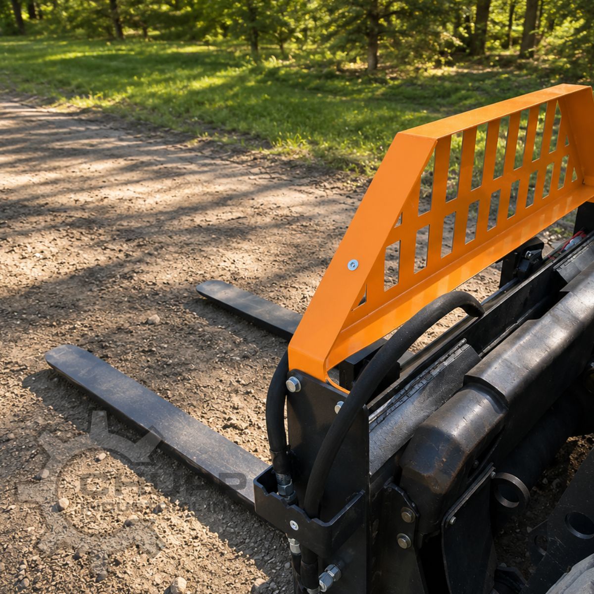 Wolverine 48-inch pallet forks mounted on a mini skid steer's quick-attach plate, orange backrest above black tines
