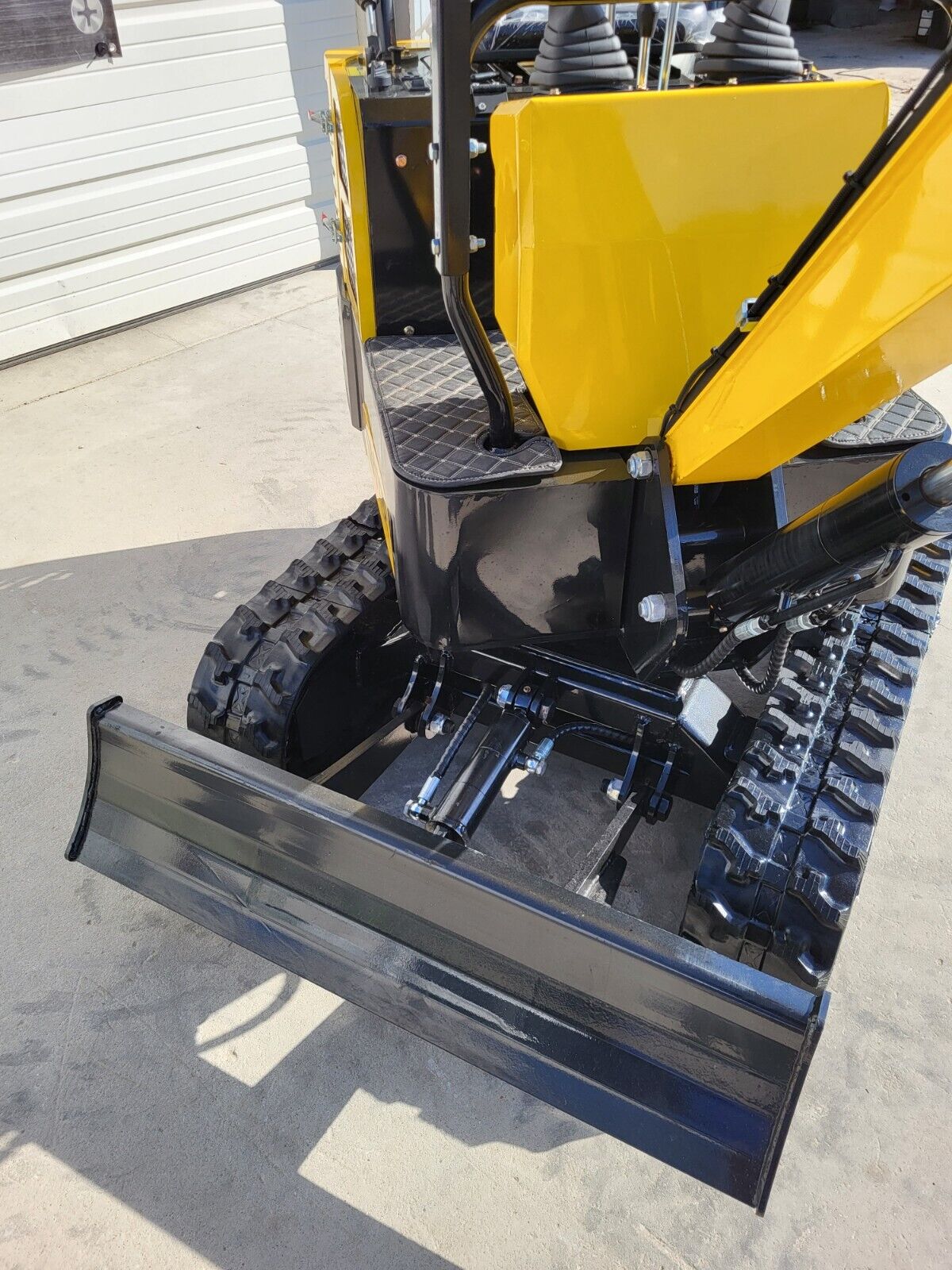 AGT QH12R backfill blade raised on its hydraulic cylinder, between the rubber tracks and undercarriage